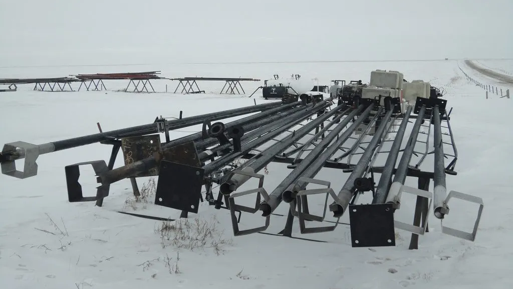 Portable flare stacks rental alberta, saskatchewan, BC, Western Canada - Inventory of dismantled rental flare stacks resting on pipe racks in a snowy Western Canadian oilfield.